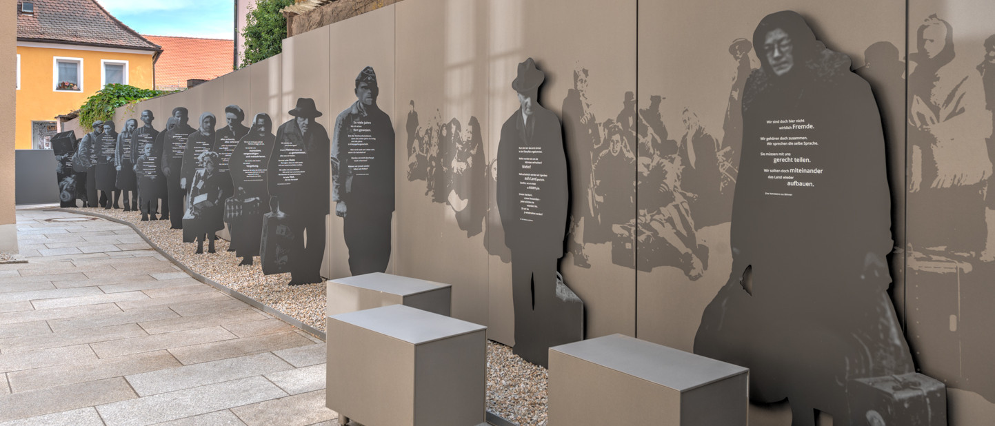 Eingangsbereich des Museums mit mehreren Metall-Figuren, die auf der Flucht dargestellt werden.